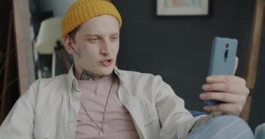 Tasasız öğrenci konuşuyor ve dairede akıllı telefonuyla el sallıyor. İletişim ve gençlik kavramı.