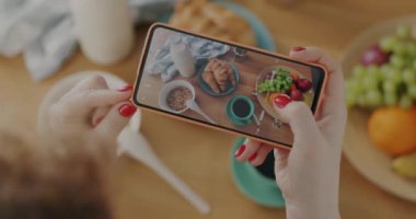 Kadın elinin akıllı telefon kullanarak yemek masasının üstünde yatarken fotoğraflarını çekerken yakın plan çekimi. Fotoğraf ve modern teknoloji kavramı.