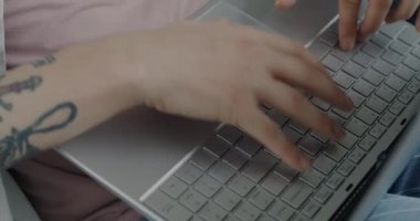 Dairenin içinde dizüstü bilgisayar kullanan dövmeli bir genç adam var. Modern teknoloji ve ev kavramından uzak iş.