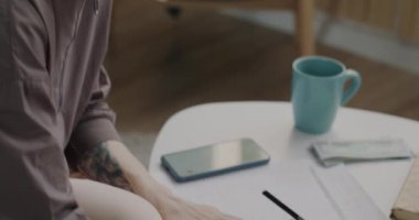 Yaratıcı saç stili olan iş kadını akıllı telefon hesap makinesiyle evde para sayıyor. Modern teknoloji ve muhasebe uygulaması.