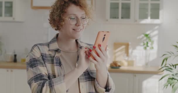 漂亮的年轻女性使用智能手机刷卡和触摸屏享受家庭厨房的在线内容 通信和社交媒体概念 — 图库视频影像