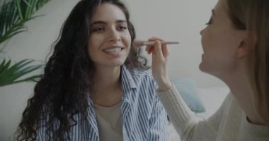 Makyaj malzemesi kullanan ve yatak odasında konuşan kaygısız kadın arkadaşlarının portresi. Güzellik ve kozmetik konsepti.