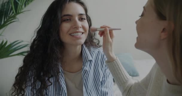 无忧无虑的女性朋友用化妆品粉刷粉底 在卧室里聊天的肖像 美容美发概念 — 图库视频影像