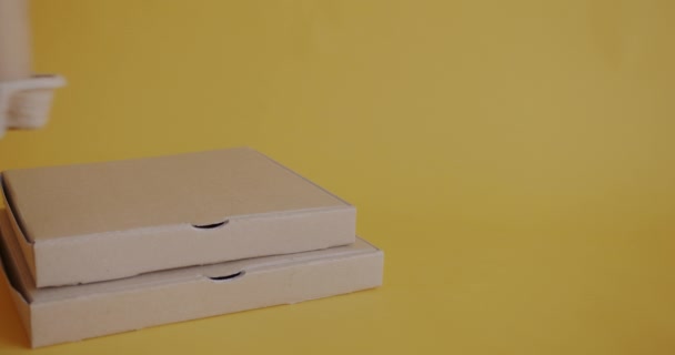 Zbliżenie Żeńskiej Dłoni Odkładanie Filiżanki Kawy Kartonowego Pudełka Pizzą Żółtym — Wideo stockowe
