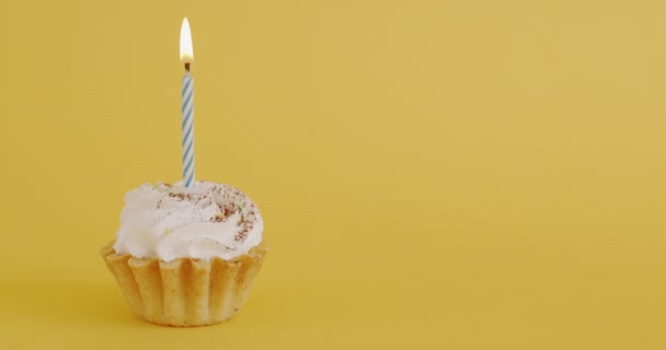 黄色を背景にキャンドルが燃えるミニ誕生日ケーキのクローズアップ 特別な機会とおいしいデザートのコンセプト — ストック動画