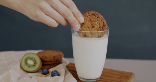 Zbliżenie Żeńskiej Dłoni Wkładającej Herbatniki Owsiane Szklanki Mleka Podczas Śniadania — Wideo stockowe