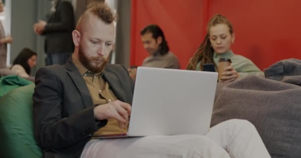 Портрет Профессионала Работающего Ноутбуком Сидящего Мягком Кресле Коворкинговом Пространстве Людьми — стоковое видео