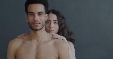 Güzel genç bir çiftin portresi. Çıplak bir şekilde ayakta durup kameraya gülümsüyor. İlişki ve samimiyet kavramı.