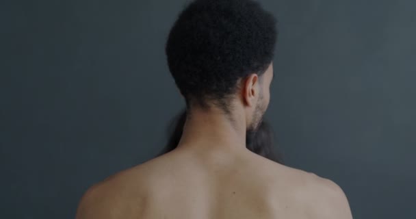 灰色の背景に立って裸のアフリカ系アメリカ人の男性と親密な瞬間の間に首を抱きしめる女性の手のバックビュー 関係と愛の概念 — ストック動画