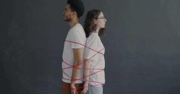 男と女の手を後ろに赤い糸で結ばれて立ってゆっくりとした動き 関係の危機とコミットメントの概念 — ストック動画