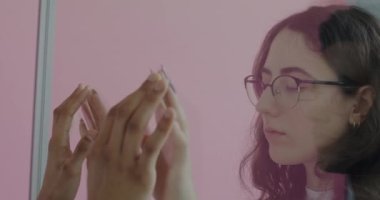 Düşünceli insanlar, Afro-Amerikalı erkek ve beyaz kadın pembe arka plandaki cam duvarın arkasından el ele tutuşuyorlar. Mesafe ve ilişki kavramı.