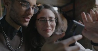 Birkaç öğrenci ekranlara dokunarak ve sohbet ederek kafede eğleniyor. Sosyal medya ve modern teknoloji kavramı.