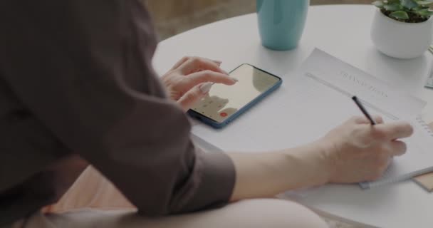 在智能手机中使用计算器与女性密切合作 并将财务信息写在家里的数钱纸上 人与会计概念 — 图库视频影像