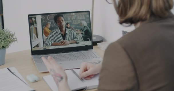 在商业人士的肩膀上看去 他们在办公室里用显示大拇指的笔记本电脑进行视频通话 女商人在网上与男同事交谈 — 图库视频影像