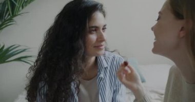 Neşeli kız, arkadaşının makyajına yardım ediyor ve yatak odasında takılıyor. Pozitif duygu ve güzellik kavramı.