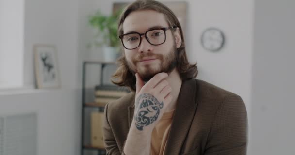 一个戴着眼镜 穿着时髦西装 手握纹身的年轻成功人士的慢动作肖像 商人面带微笑地看着相机 — 图库视频影像