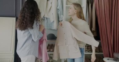 Neşeli bayan öğrenciler kıyafetlerini ve aksesuarlarını dolaptan seçiyorlar evde eğleniyorlar. Moda ve arkadaşlık kavramı.