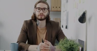 Dövmeli genç adam konuşuyor. Video araması yapıyor ve ofiste onayını veriyor. İş iletişimi ve elektronik sigara kavramı.