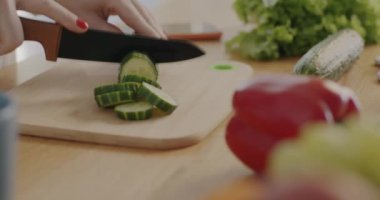 Kadın eli, sebze doğrarken bıçakla salata pişirirken ve mutfakta tahta tahta kullanırken yakın plan. Aşçılık ve sağlıklı beslenme konsepti.
