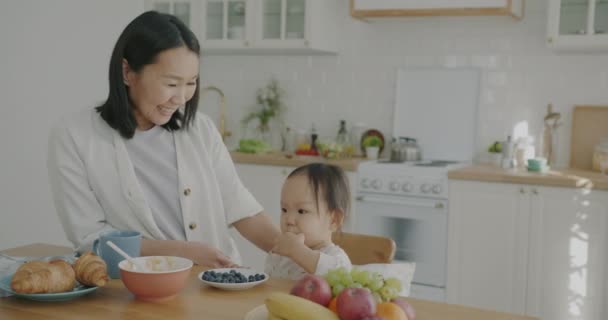 Criança Bonito Comer Frutas Frescas Enquanto Mãe Senhora Asiática Falando — Vídeo de Stock