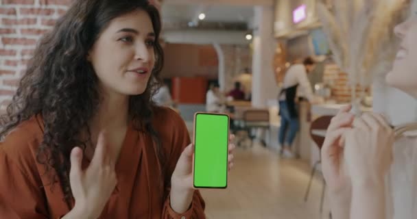 Молодая Женщина Показывает Зеленый Экран Хрома Ключ Смартфона Подруги Кафе — стоковое видео