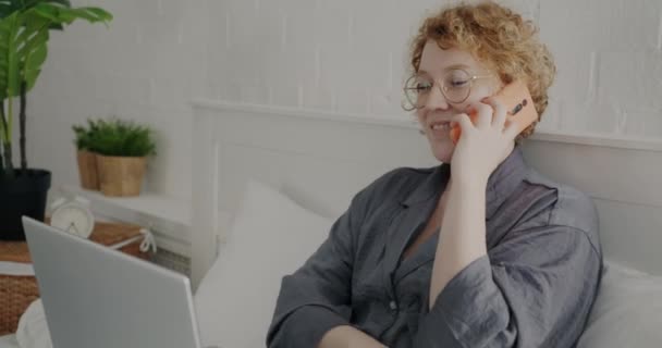 Portret Wesołej Damy Piżamie Rozmawiającej Przez Telefon Komórkowy Korzystającej Laptopa — Wideo stockowe