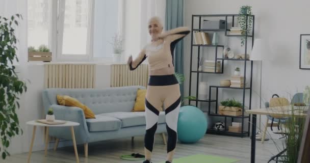 Modern Kıyafetli Narin Yaşlı Bir Kadının Oturma Odasında Spor Yapan — Stok video