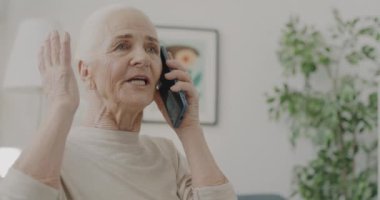 Mutlu, emekli bir kadın cep telefonuyla sohbet ediyor. Evde konuşmanın ve aramanın tadını çıkarıyor. Modern teknoloji ve iletişim konsepti.