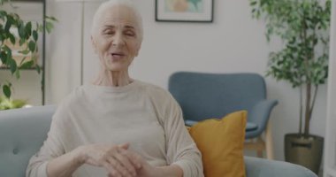 Son sınıf öğrencisinin portresi, evdeki kameraya bakarak el sallıyor ve çevrimiçi video görüşmesinden keyif alıyor. İletişim ve emeklilik kavramı.