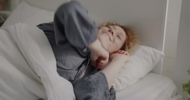穿着睡衣的快乐女孩的画像在卧室里醒来 张开双臂 在床上微笑 人与早晨例行公事概念 — 图库视频影像