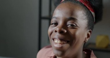 Kapalı alanda gülümseyen ve gülen Afrikalı Amerikalı kadının yavaş çekim portresi. İnsanlar ve mutluluk kavramı.