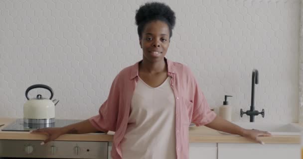 站在厨房里的快乐的非洲裔美国家庭主妇慢镜头 微笑着看着相机 公寓和家庭生活方式概念 — 图库视频影像