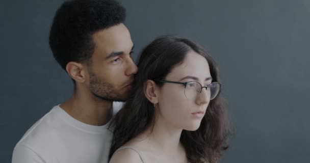 有爱心的年轻人在女朋友耳边窃窃私语 表达着一起站在灰色背景上的感情 爱情和关系概念 — 图库视频影像