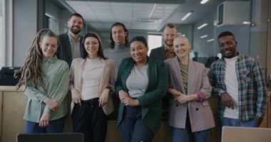 Ortak ofiste kameraya bakarak gülümseyen neşeli erkek ve kadın meslektaşların portresi. İş yeri ve mesleki meslek kavramı.