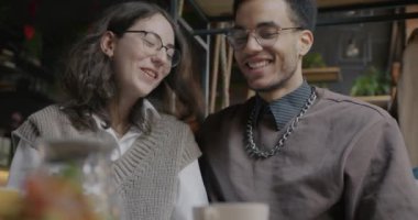 Genç ve mutlu bir çift kahkaha atıyor, kahkaha atıyor ve kafede kahve içiyor. Romantik ilişki ve olumlu duygu kavramı.