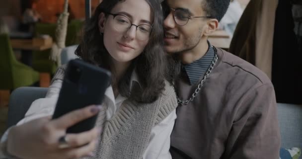 カフェでキスをしているスマートフォンのカメラで自画撮りをする恋人夫婦のスローモーション 関係性と近代技術の概念 — ストック動画
