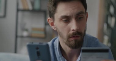 Akıllı telefon ve kredi kartıyla para transferi yapan neşeli genç adam. Çevrimiçi alışveriş ve teknoloji kavramı.