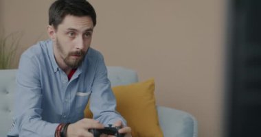 Oyun oynayan neşeli genç adamın portresi joystick ve TV ile apartmanda eğleniyor. Modern teknoloji ve oyun ekipmanları konsepti.