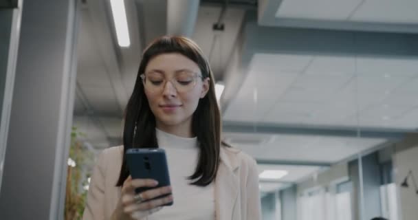 Dolly Shot Cheerful Young Businesswoman Using Smartphone Smiling Walking Office — Stock Video
