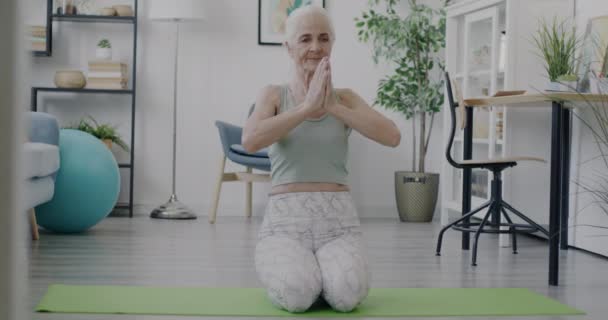 退休妇女做瑜伽和在垫子上放松的慢动作 享受在家里的练习 冥想和闲暇时间活动概念 — 图库视频影像