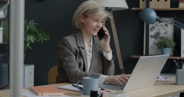 Ofiste Cep Telefonuyla Konuşan Dizüstü Bilgisayar Kullanan Neşeli Kadınının Portresi — Stok video