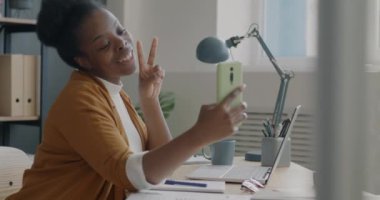 Oyuncu genç bayan ofis çalışanı akıllı telefonuyla selfie çekiyor iş yerinde eğleniyor. Fotoğraf ve teknoloji konsepti.