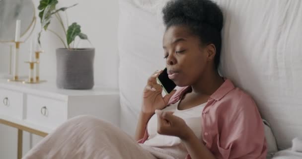 快乐的女生在手机上聊天 在床上放松 在公寓里聊天和微笑 现代生活方式和交流概念 — 图库视频影像