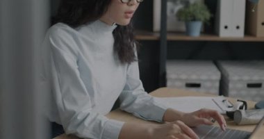 Ofiste masa başında dizüstü bilgisayar kullanıp gözlük takan Asyalı şık bir ofis çalışanı. İstihdam ve kariyer geliştirme kavramı.