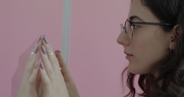 ピンクの背景にガラスの壁を通して手に触れる男と女の出産カップルのスローモーション 関係性と演劇の概念 — ストック動画