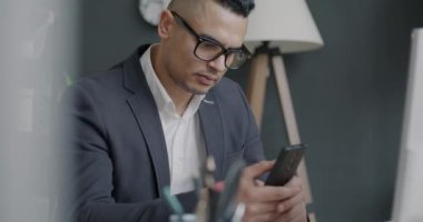 Orta Doğulu ofis çalışanlarının portresi iş yerinde iletişim kuran ve gülümseyen akıllı telefonları kullanıyor. İş ve modern aygıt kavramı.