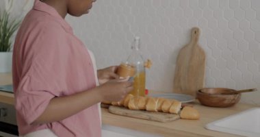 Afrika kökenli Amerikalı bir kadının fıstık ezmesini ekmeğe sürerken ve evde sandviç yaparken yavaş çekimde çekilmiş bir portresi. Yemek ve yemek konsepti.