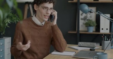 Cep telefonuyla konuşan ve modern ofiste dizüstü bilgisayarla çalışan neşeli işçilerin portresi. İş iletişimi ve çalışanlar kavramı.