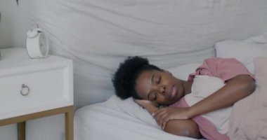 Afro-Amerikalı bir kadın sabah yatak odasında uyanıp esneyerek uyanıyor. Yurt içi rahat yaşam ve insan konsepti.