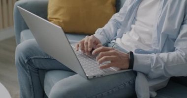 Evdeki kanepede oturup e-öğrenmenin keyfini çıkaran adamın portresi. Modern teknoloji ve eğitim kavramı.